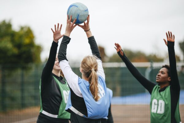 Female Netball Teams Throwing Ball On Netball Court